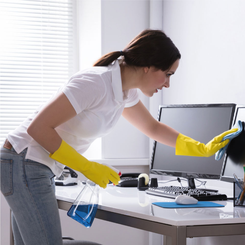 Lady cleaning office space, applying cleaning solution.