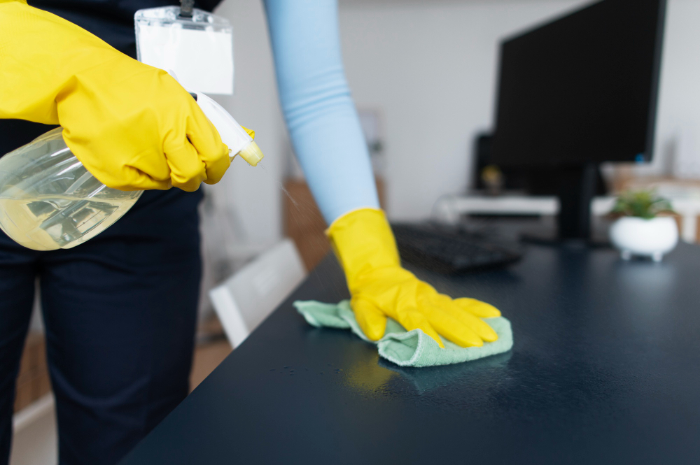 Office cleaning being performed, office table wipe with cleaning solution.