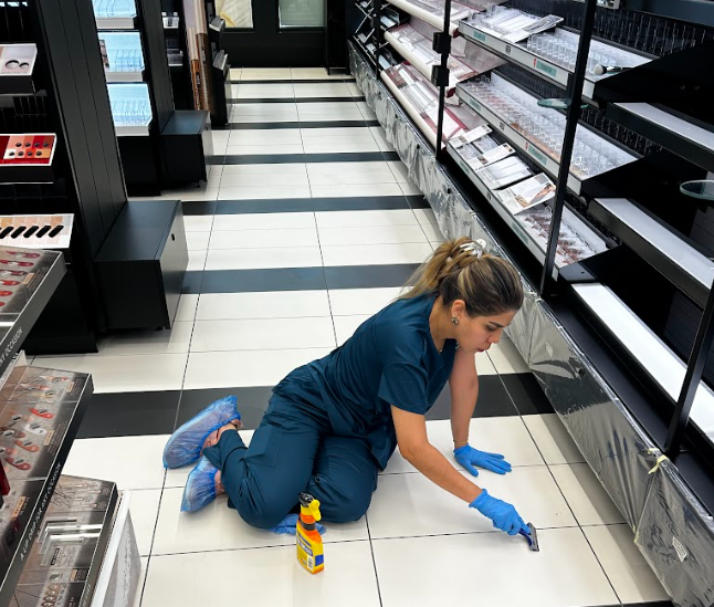 Retail store cleanign service performed, woman scrubbing floor.