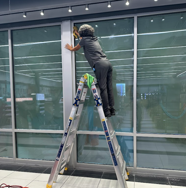 Women performing commercial cleaning service, cleaning windows of a business.