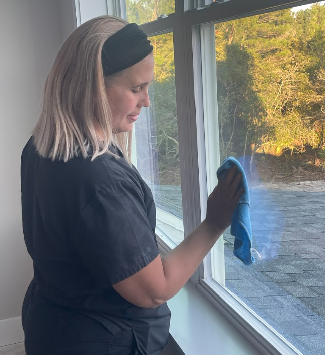 Post construction cleaning service, woman wiping windows of remodeling project.