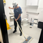 Cleaning team cleaning bathroom space, women wiping bathroom floor.