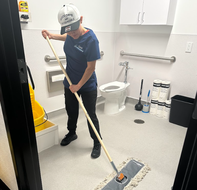 Cleaning team cleaning bathroom space, women wiping bathroom floor.