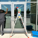 Retail cleaning service performed, woman wiping window of the store.